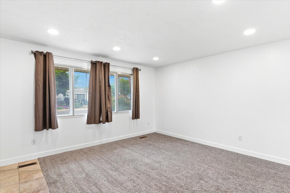 Bright interior space featuring white walls and a combination of carpet and tile flooring