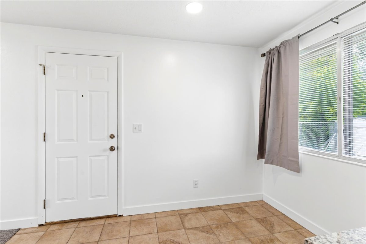 Entryway featuring a paneled door with brass hardware, tile flooring, and a window with blinds