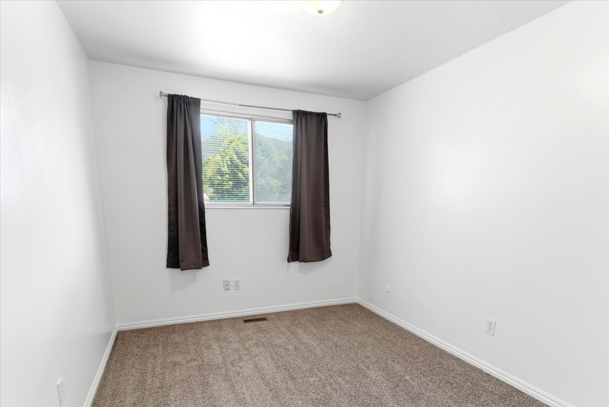 Room featuring a single window with horizontal blinds, neutral wall paint, and beige carpeting