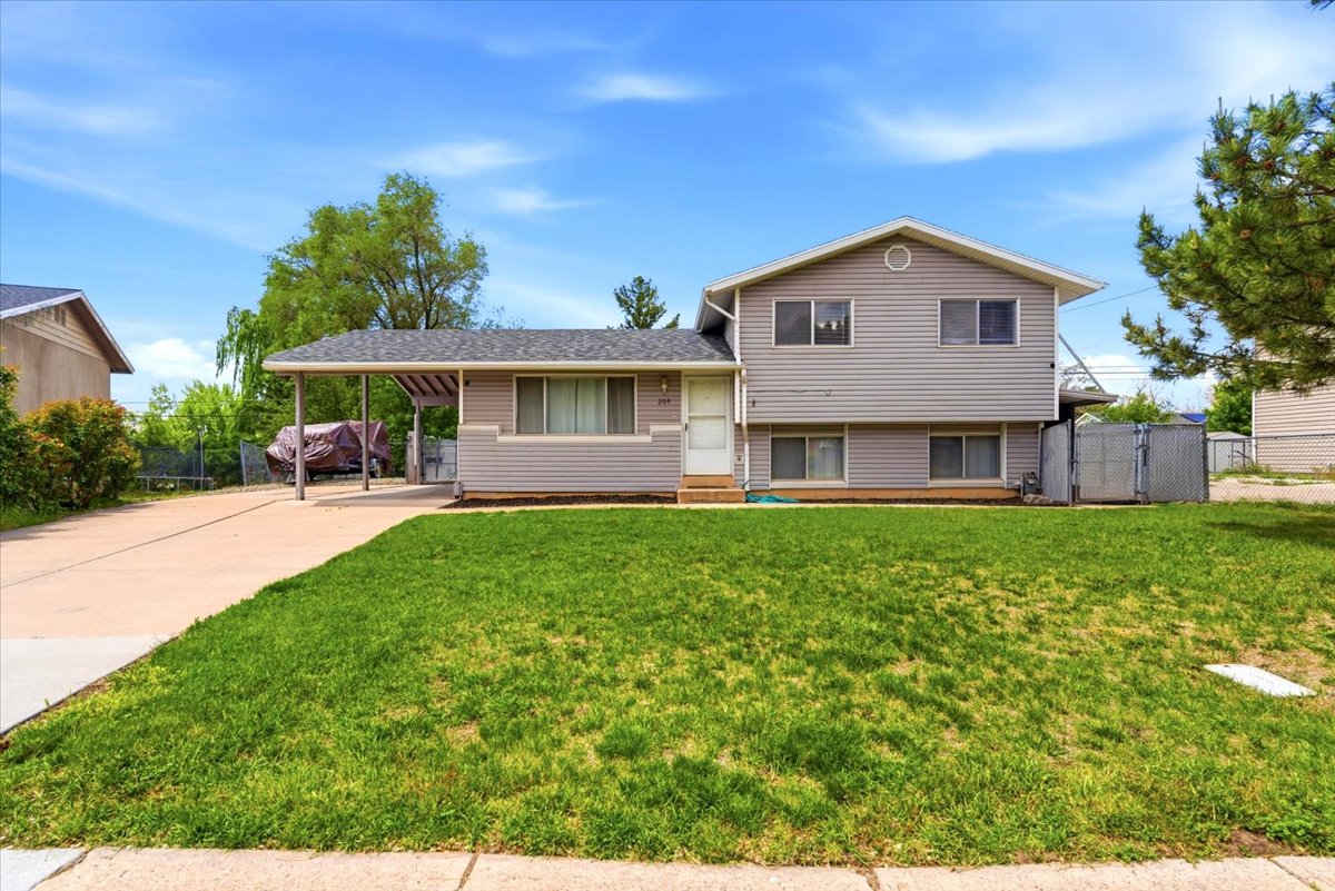 Two-story residence featuring light gray siding, an attached carport, and a front lawn
