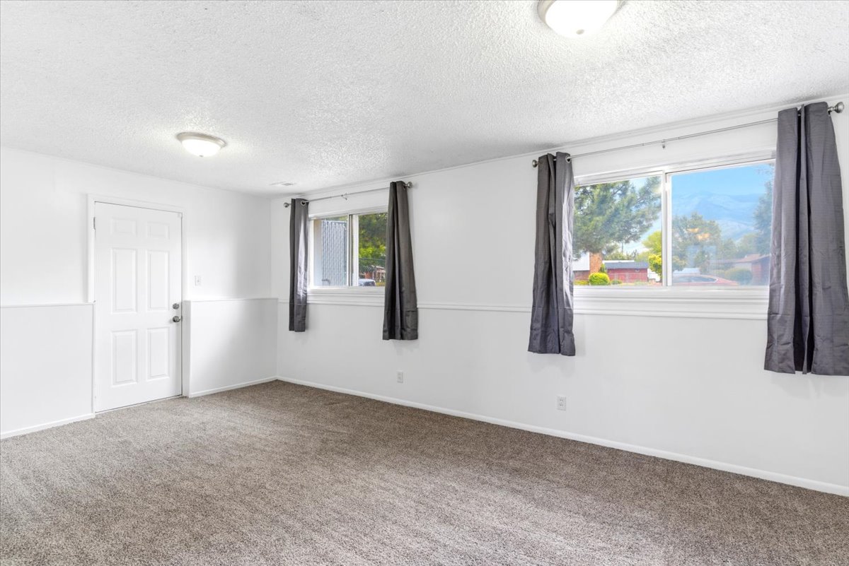 Spacious room featuring carpeting, white walls with wainscoting, and multiple windows