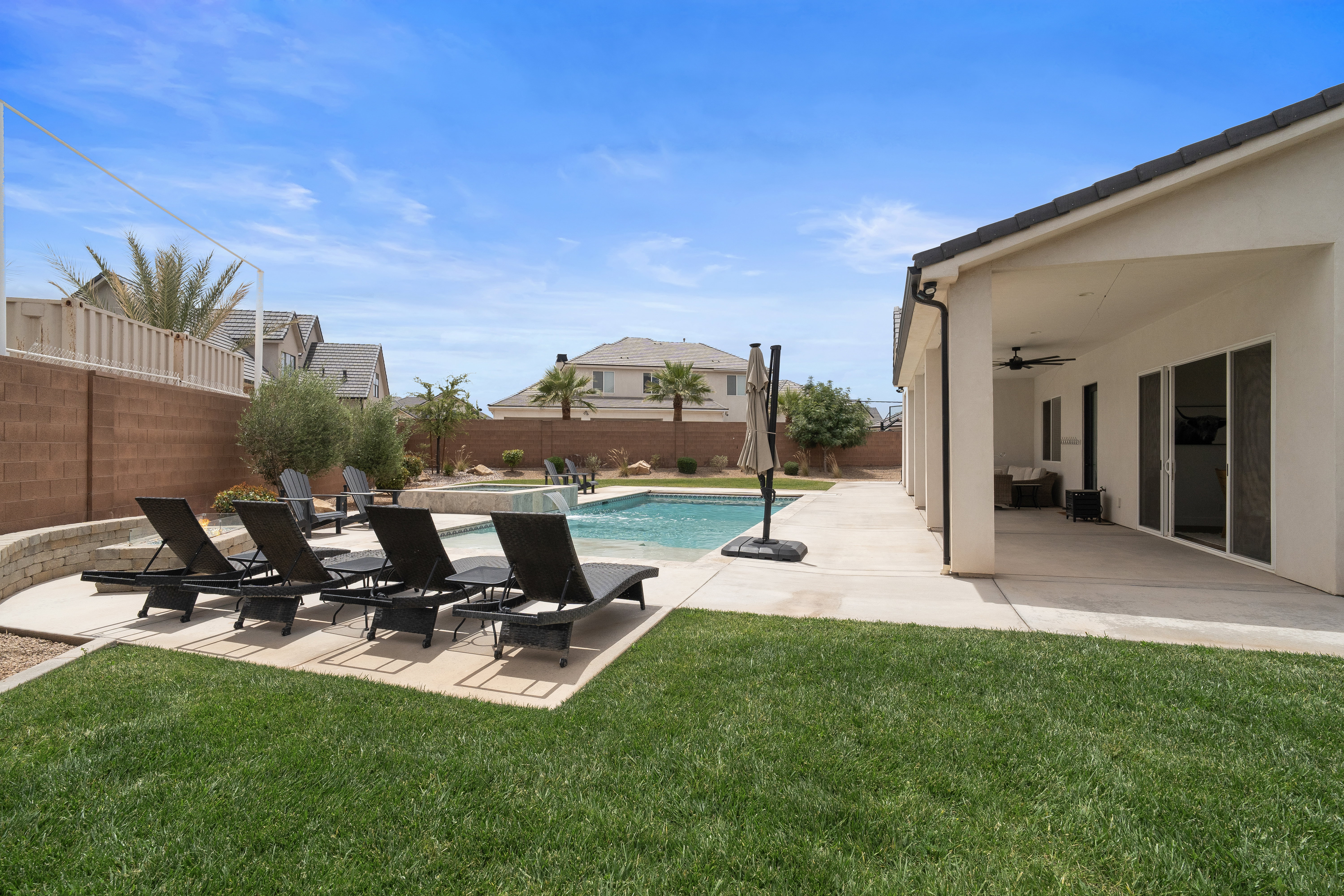 Expansive outdoor living area featuring a swimming pool, integrated spa, and concrete patio.