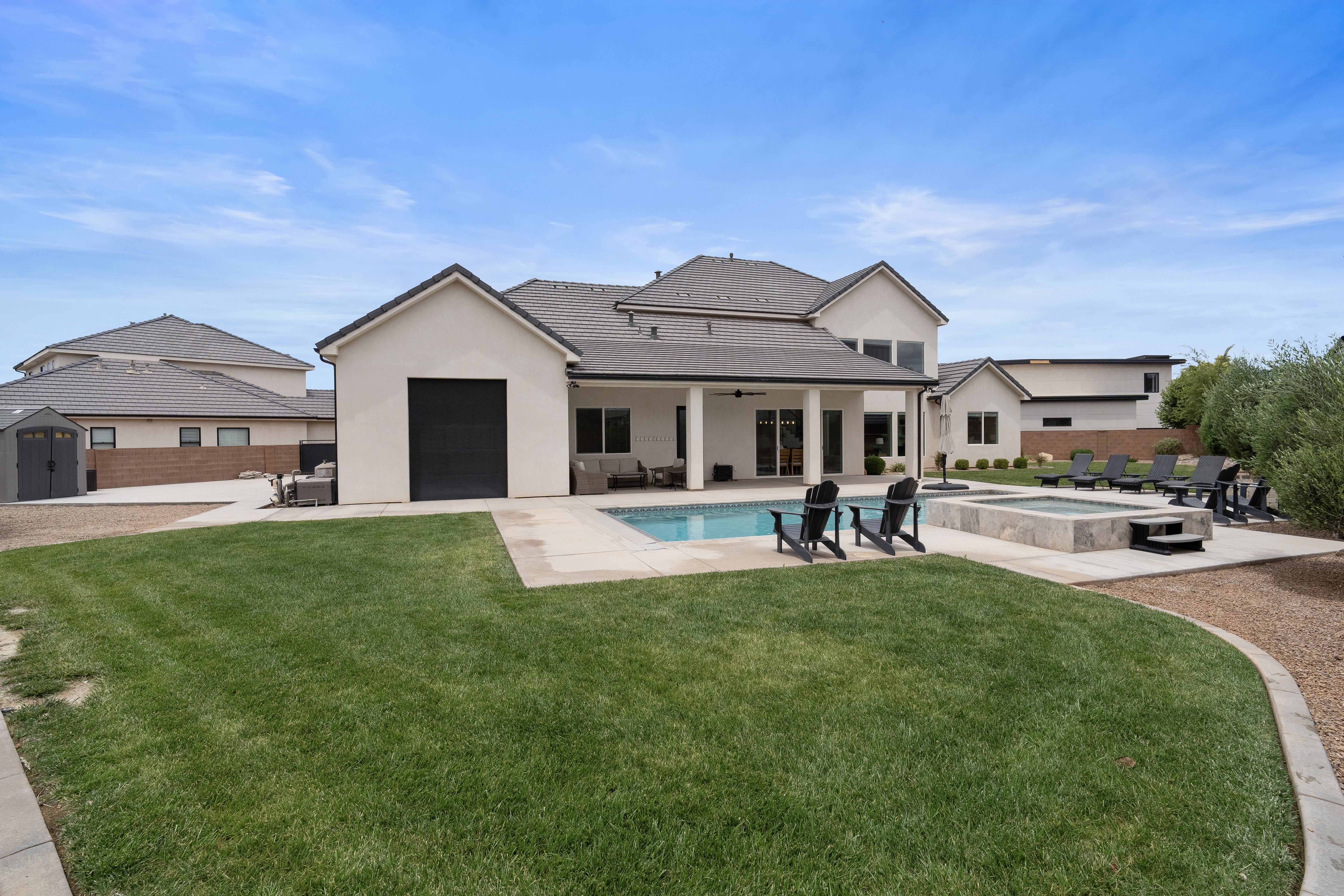 Expansive rear yard featuring a rectangular swimming pool, integrated spa, and a concrete patio surround.