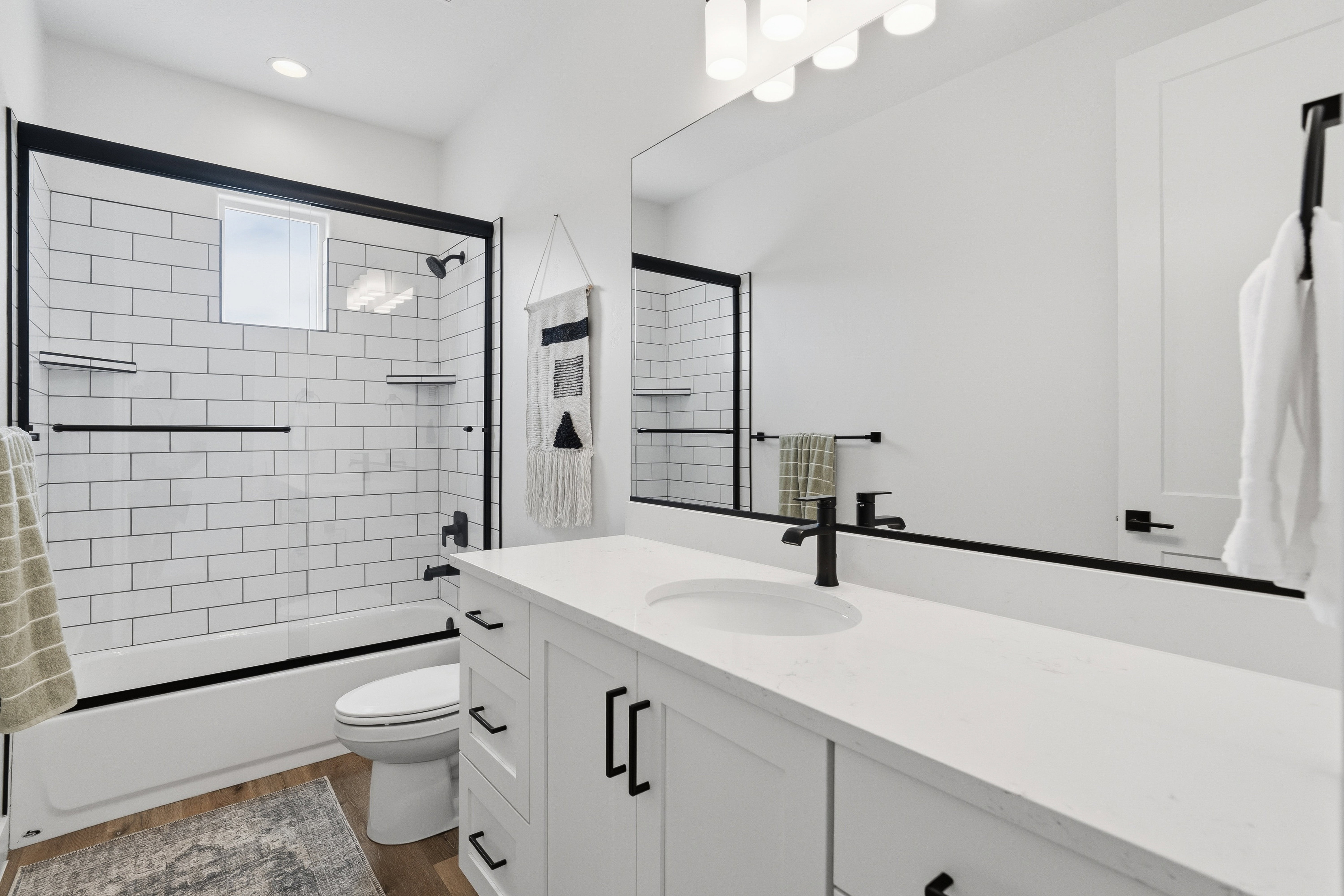 White subway tile shower surround with black-framed glass enclosure.