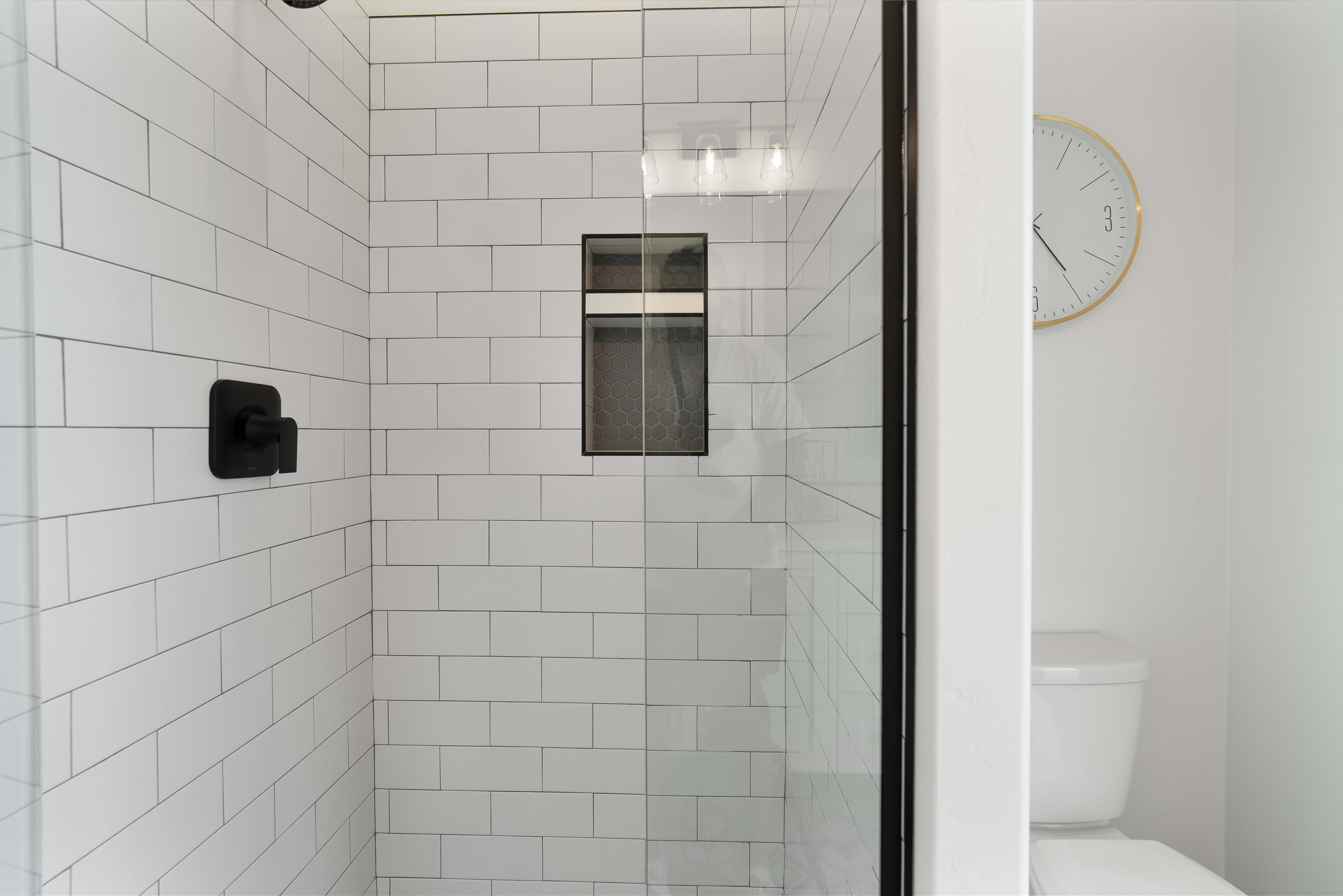 Shower enclosure featuring subway tile walls, a built-in shower niche, and a matte black shower fixture.