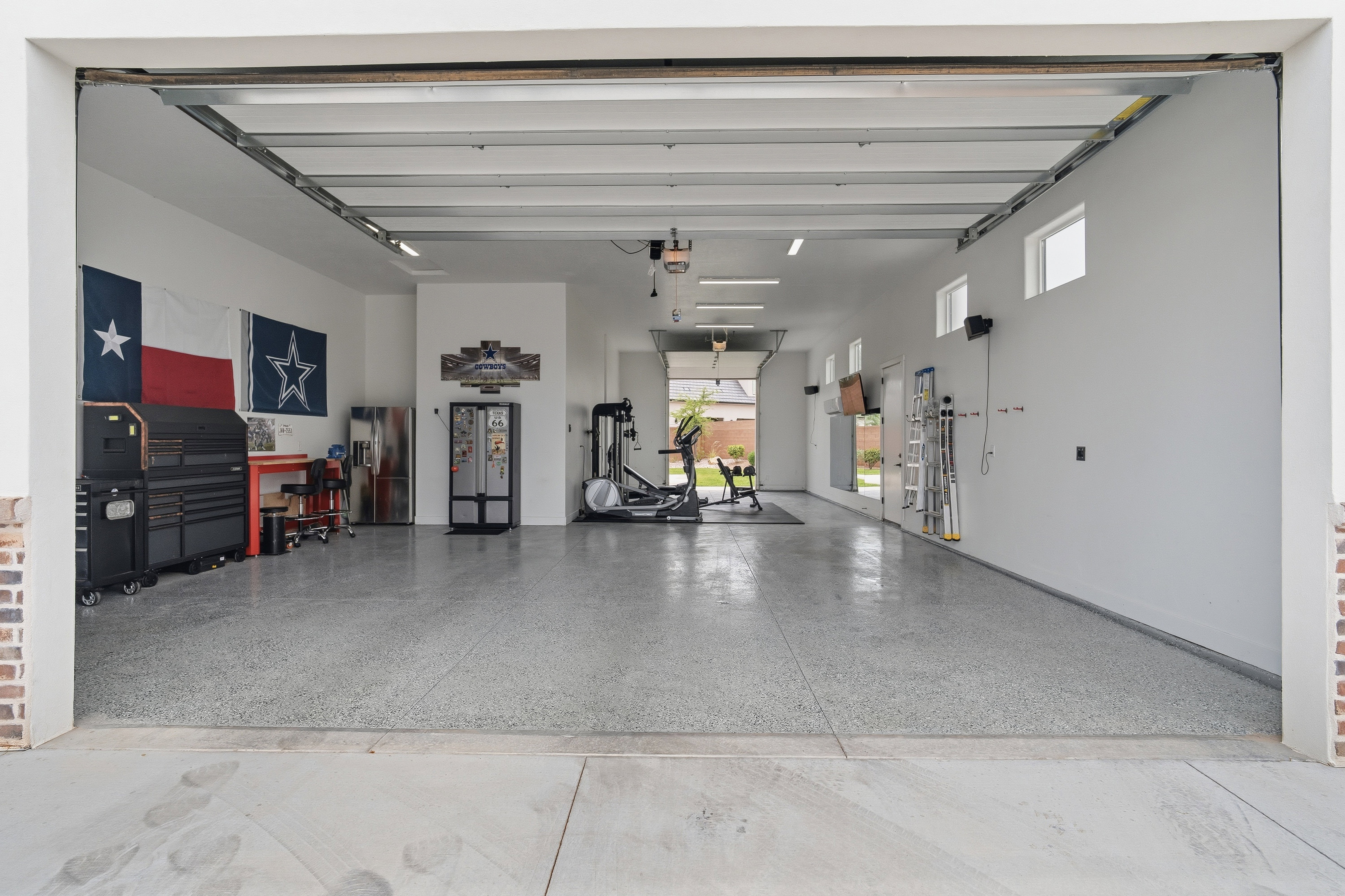Spacious garage featuring a durable epoxy floor, multiple windows for natural light, and a brick-finish entry.