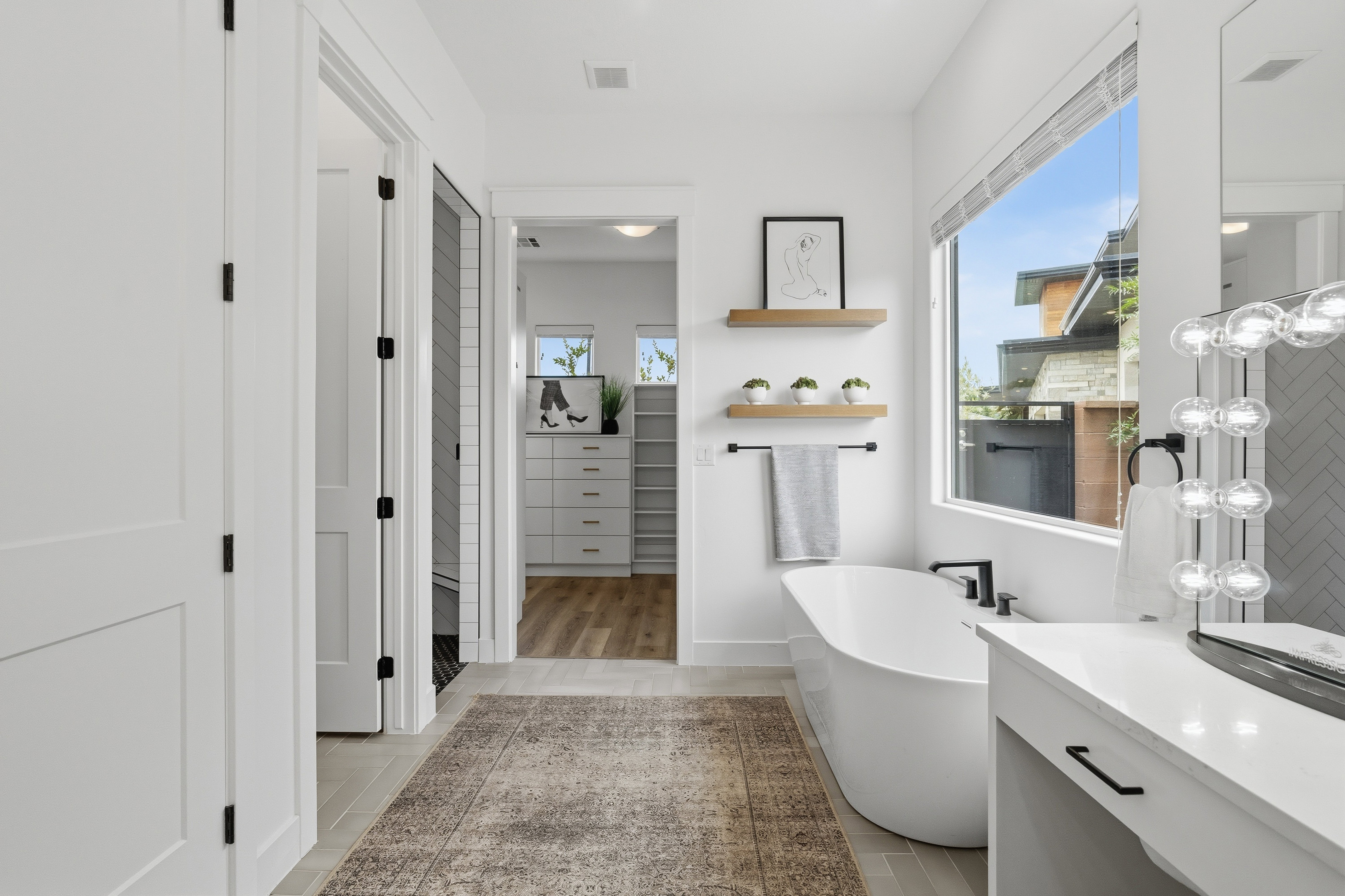 Freestanding soaking tub with matte black fixtures, complemented by a large window.