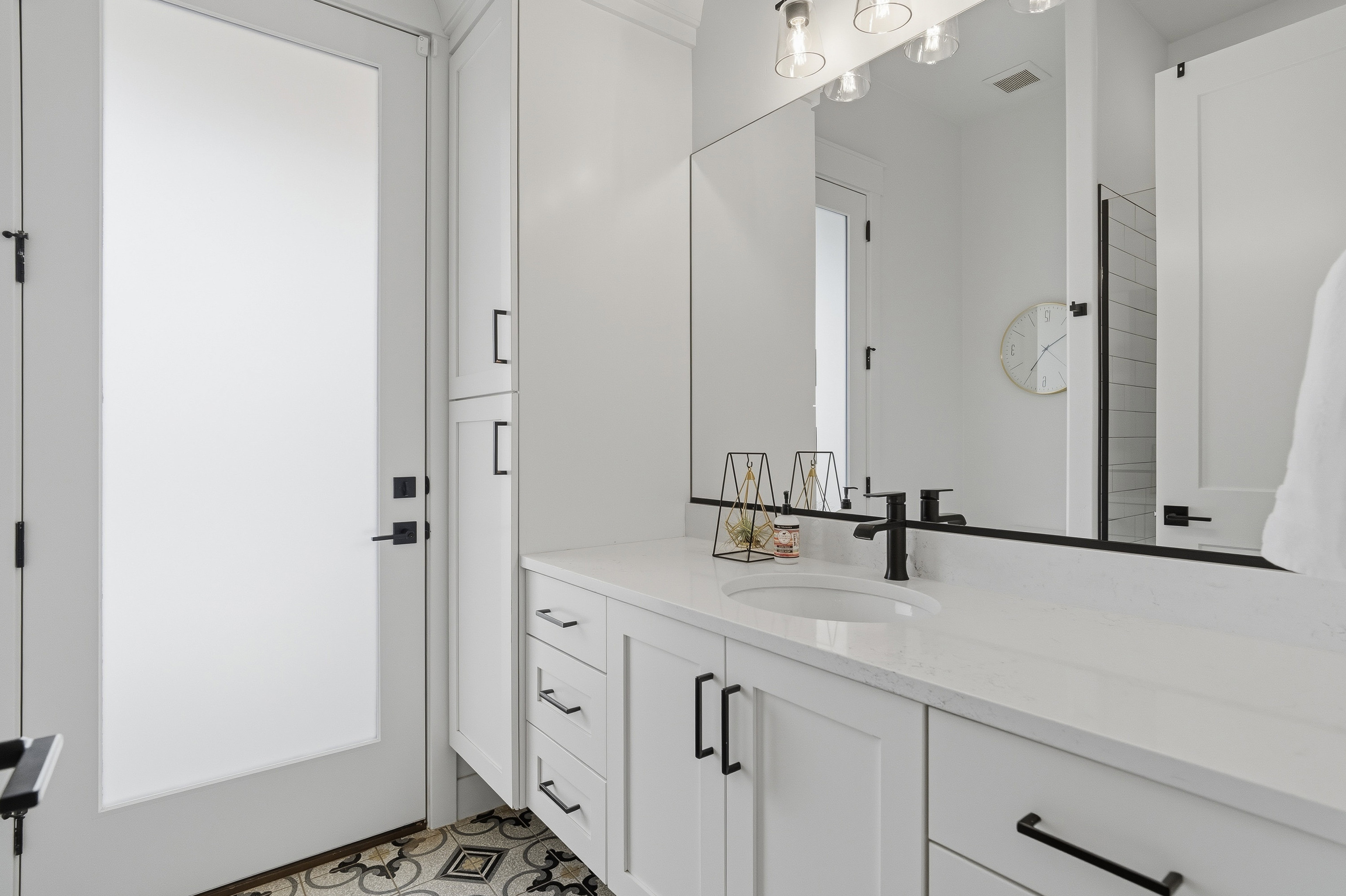 Bathroom vanity featuring an integrated sink, white countertop, and dark hardware.