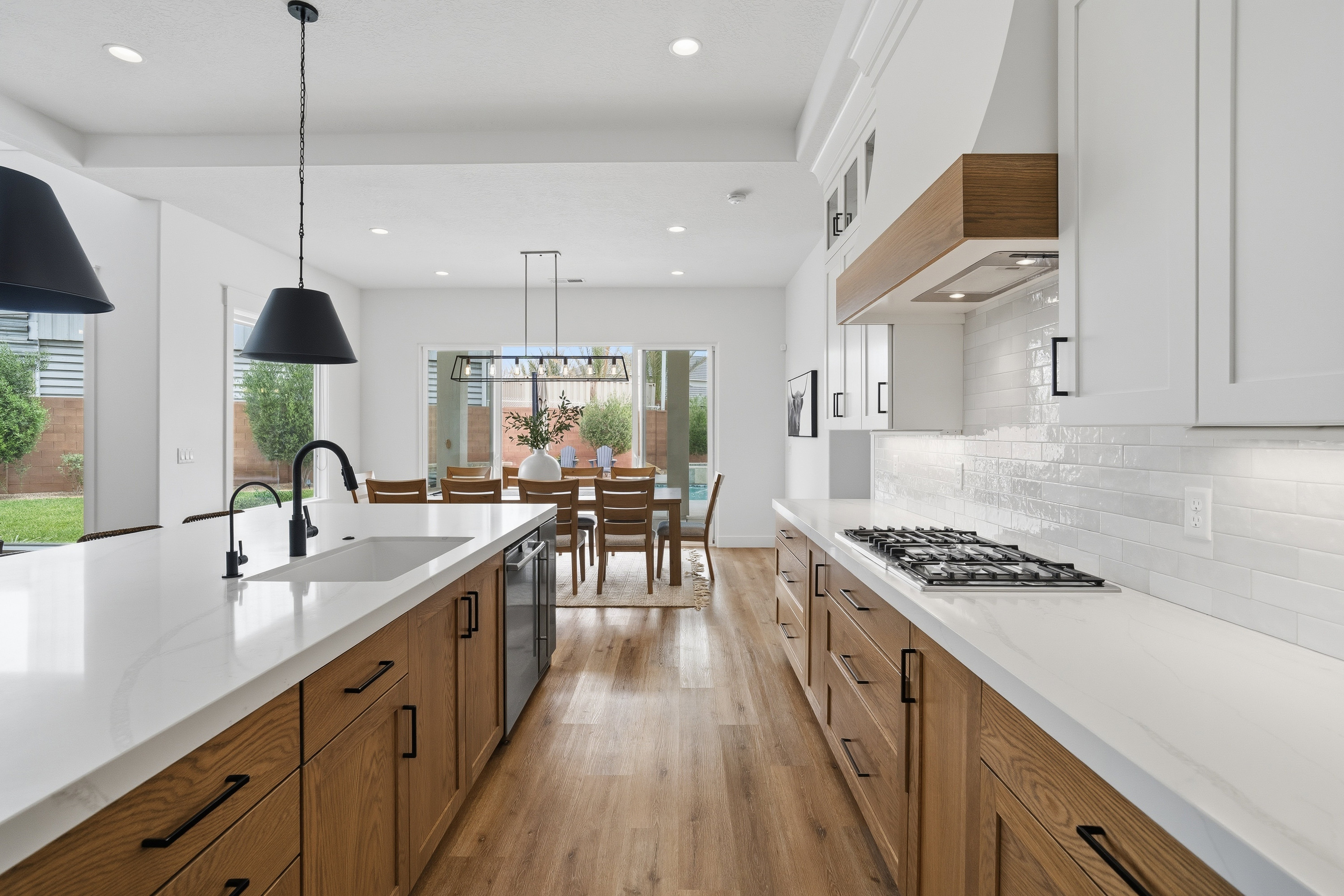 Modern kitchen with light wood-finish cabinetry, white countertops, and a subway tile backsplash.