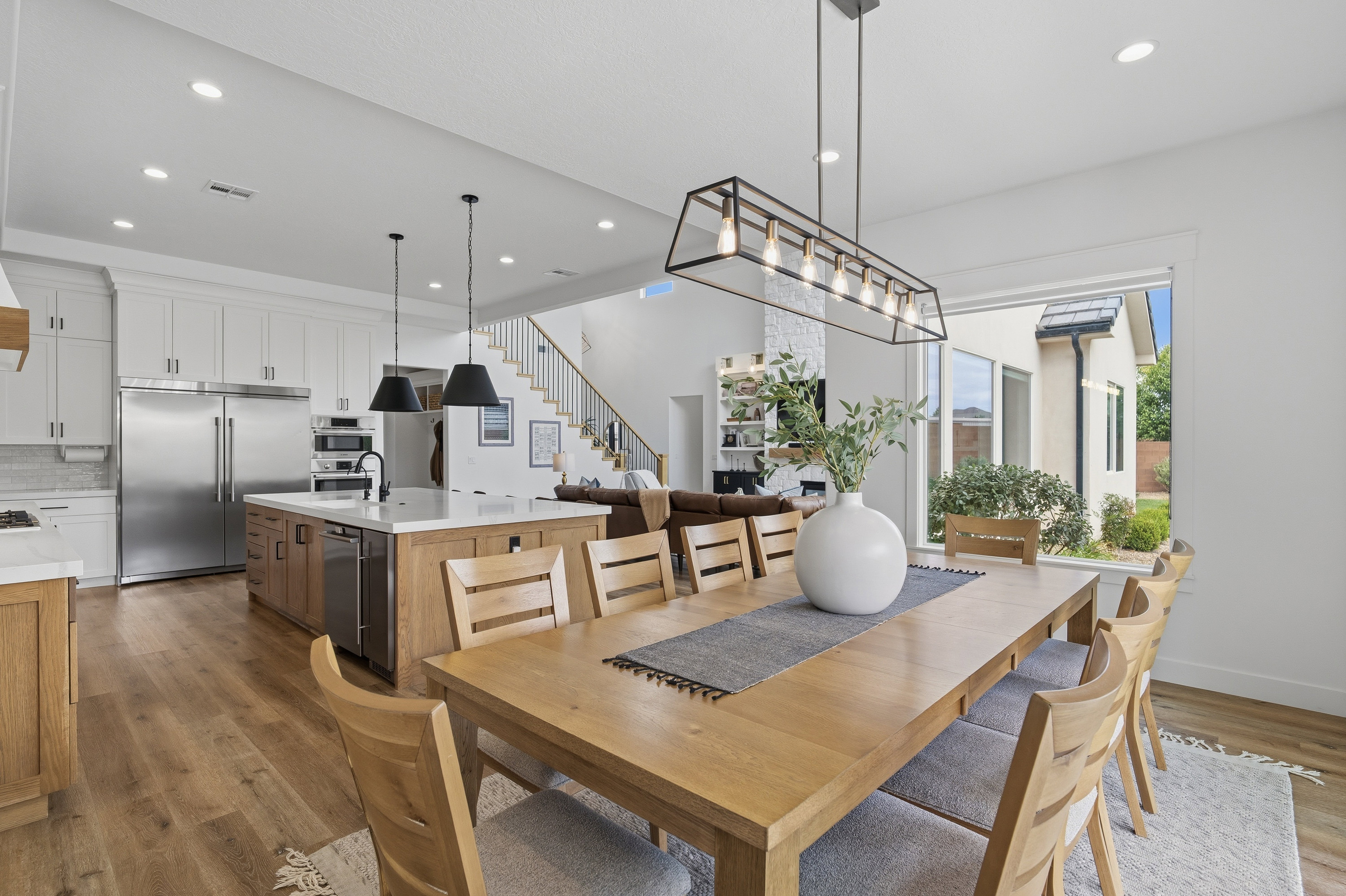 Open-concept dining area with wood-finish flooring and a contemporary linear chandelier.