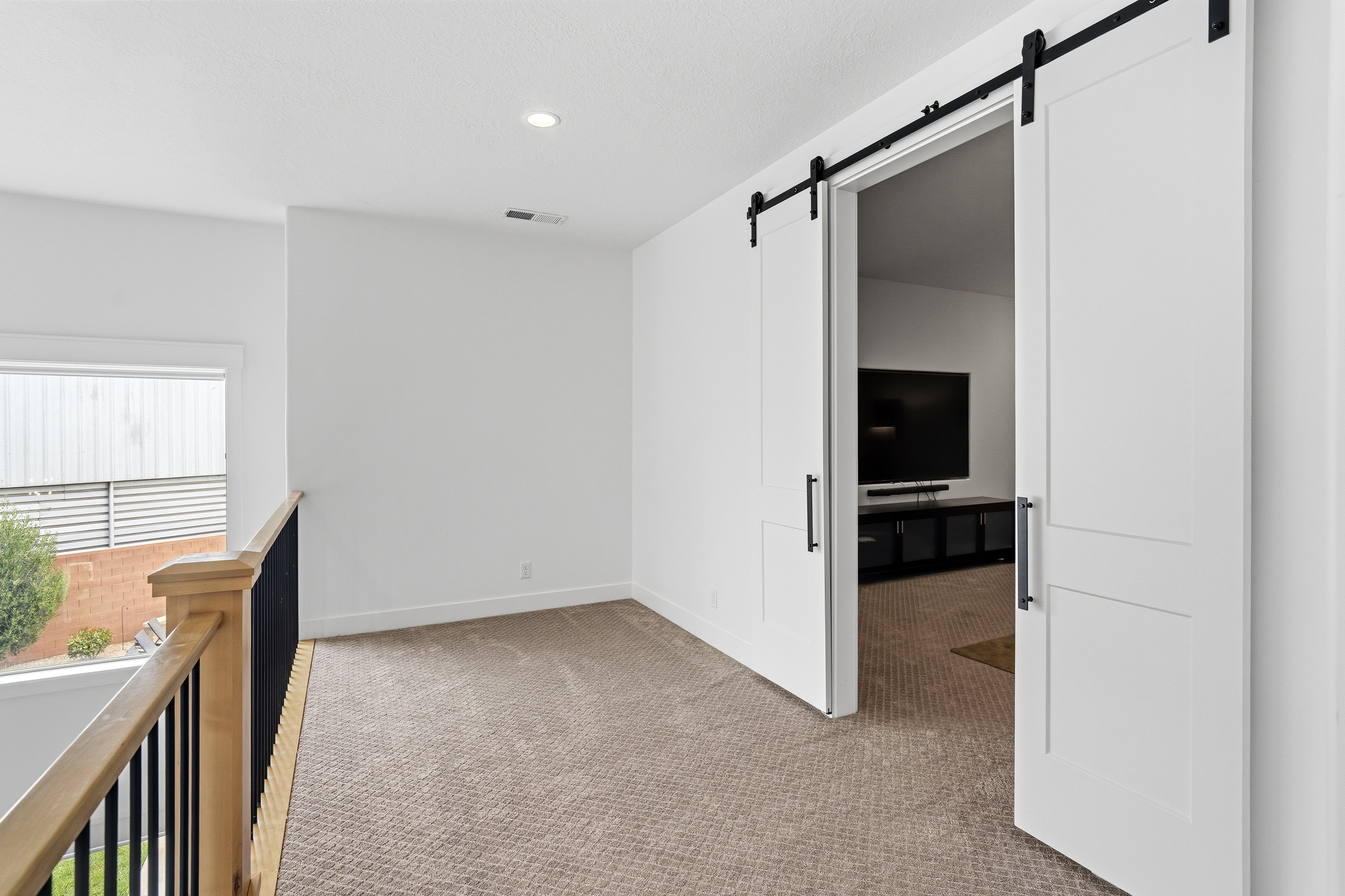 Loft area featuring a neutral carpet, white walls, and recessed lighting.