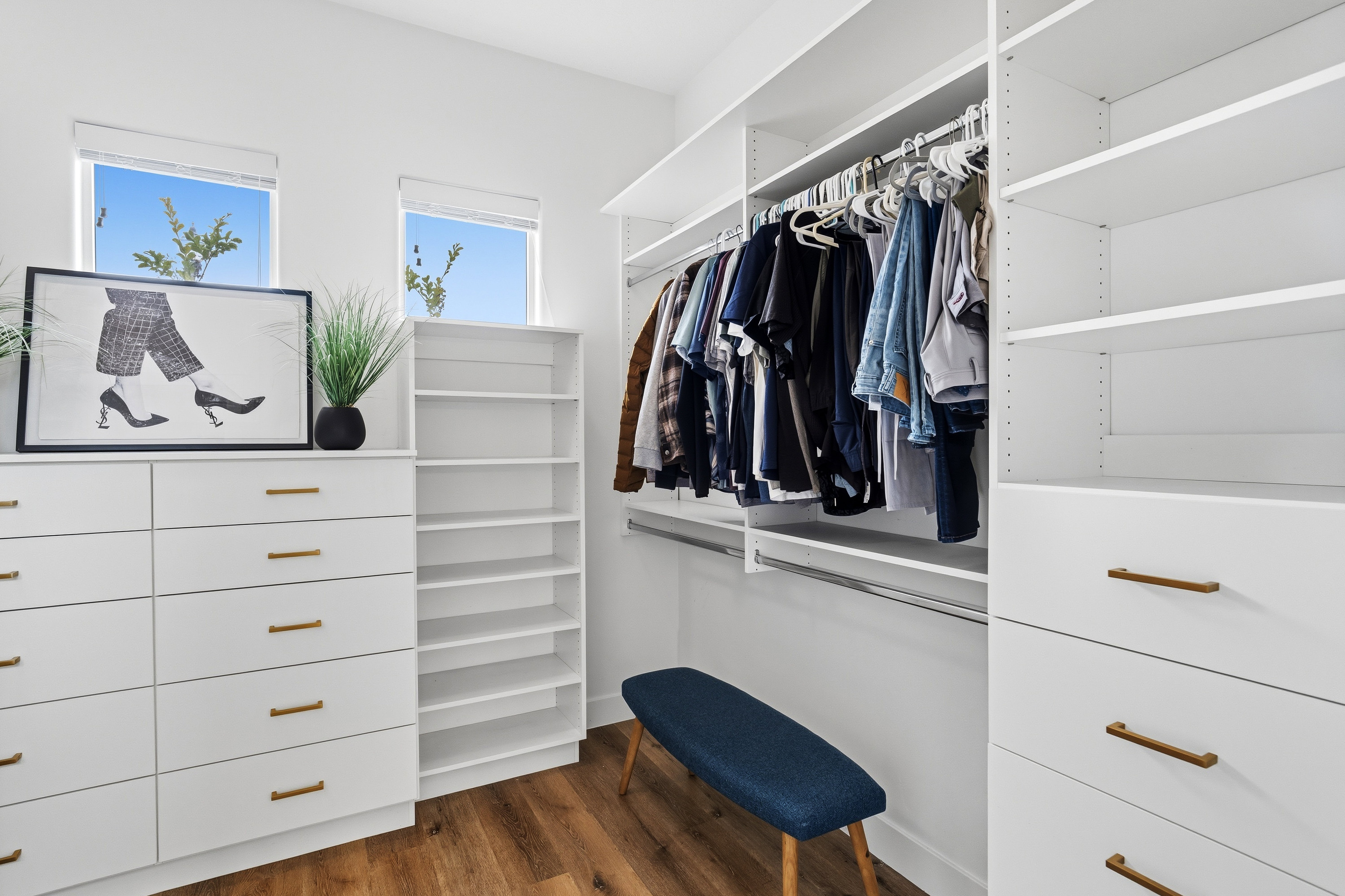 Custom closet system featuring white built-in cabinetry, shelving, and hanging rods.