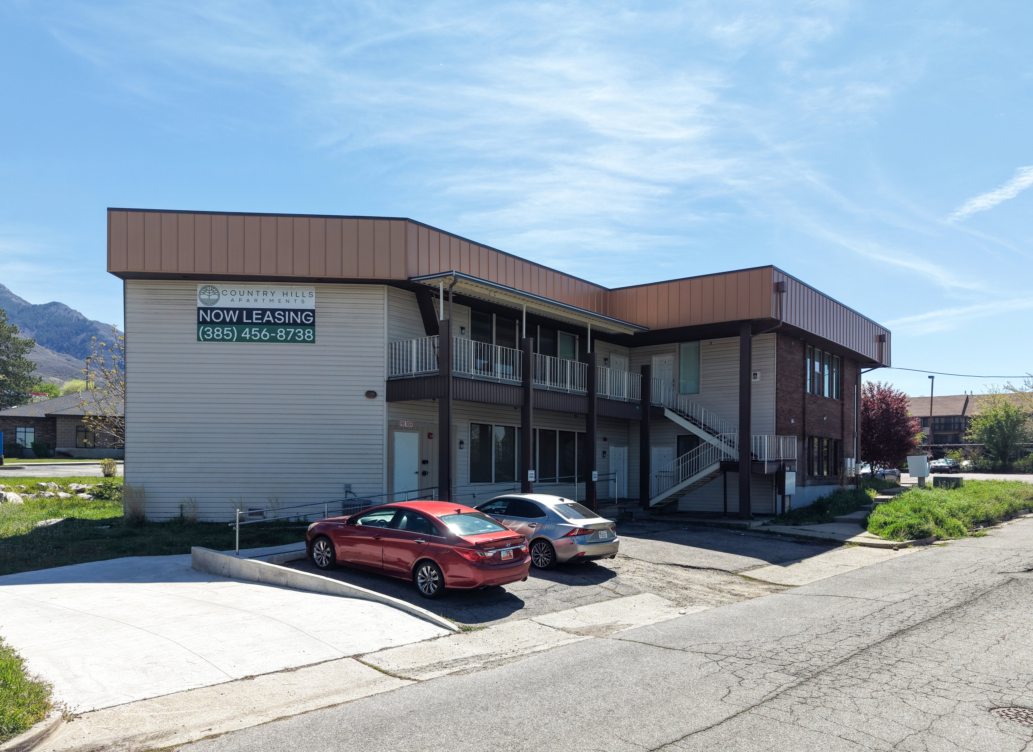 Multi-story building featuring light-colored siding and a contrasting dark brown fascia