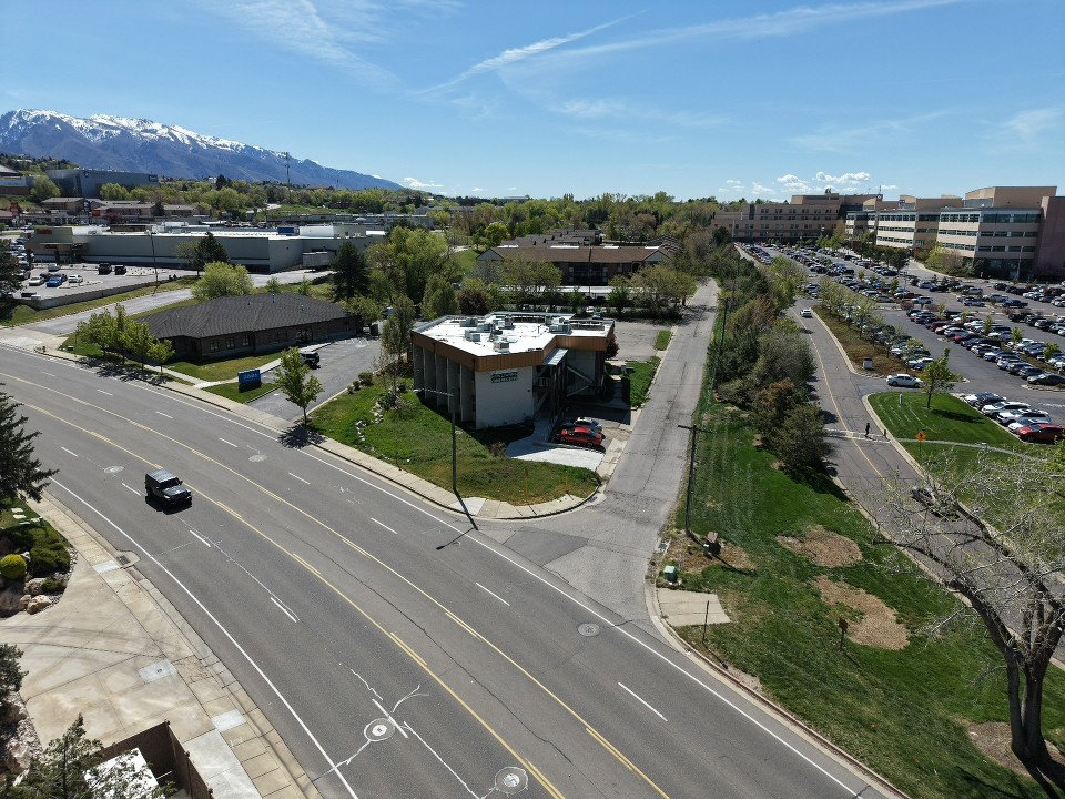 Commercial property featuring a contemporary stucco and glass facade, multiple parking areas, and mature landscaping