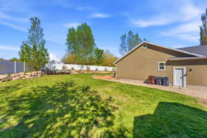 Expansive green lawn with a tiered rock retaining wall and a white vinyl privacy fence