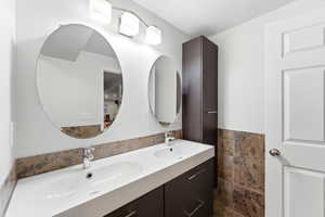Double vanity with integrated sinks, two round mirrors, and chrome fixtures