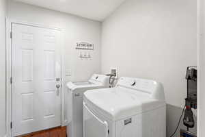 Dedicated laundry area featuring a paneled white door, wood-finish flooring, and a wall-mounted utility hook rack