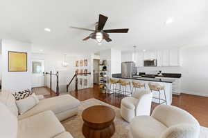 Open-concept living area featuring rich wood-finish flooring, recessed lighting, and a contemporary ceiling fan