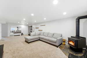 Spacious room with a wood-burning stove on a slate tile hearth, recessed lighting, and light-toned carpet flooring