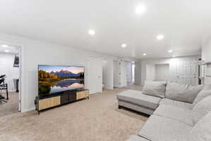 Spacious carpeted living area featuring recessed lighting, multiple interior doors, and a built-in media niche