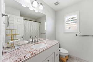 Full vanity featuring a single undermount sink, dual polished chrome faucets, and a speckled countertop