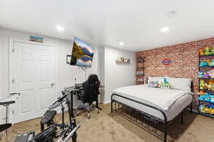 Bedroom featuring a textured accent wall, recessed lighting, and carpeted flooring