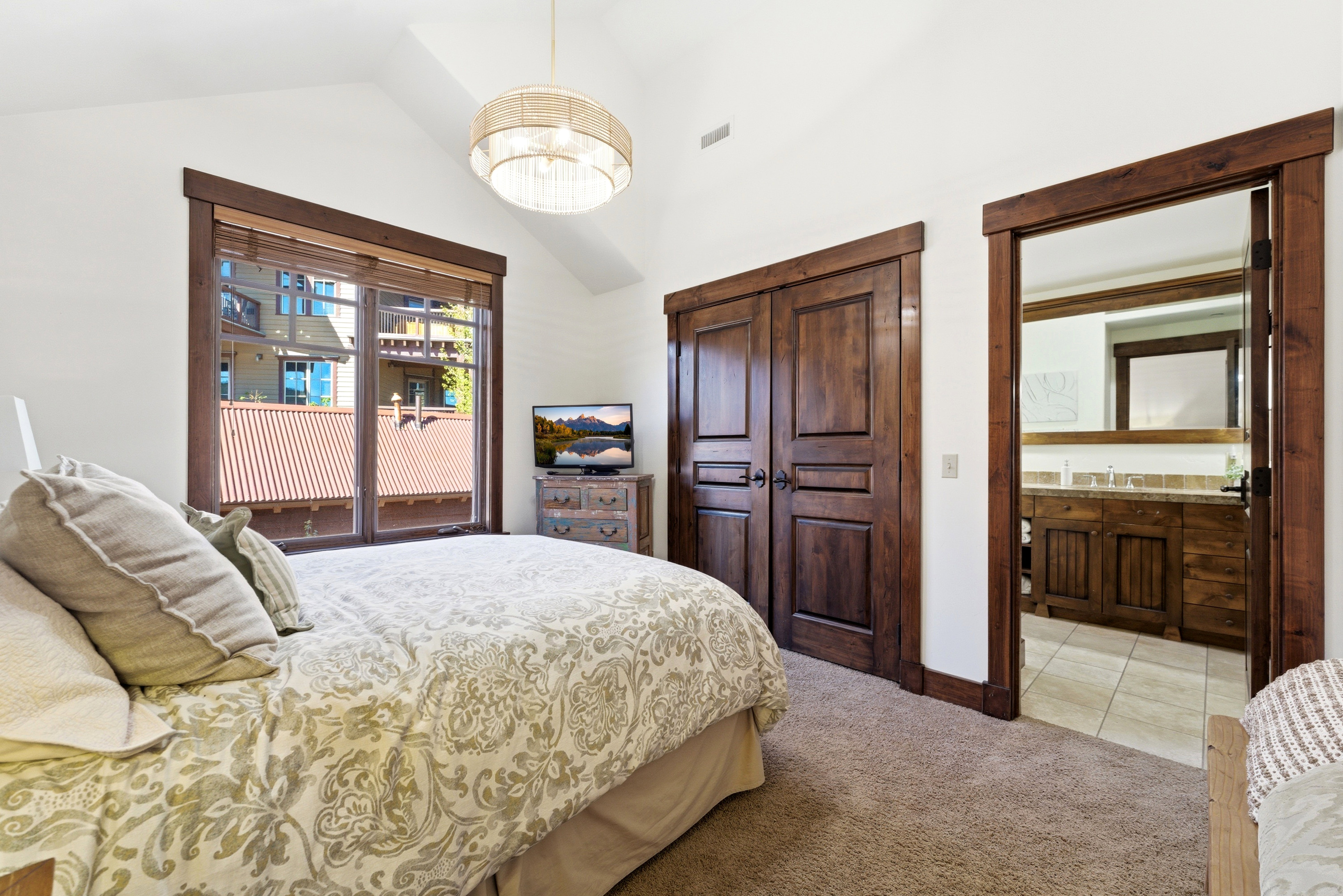 Carpeted room with vaulted ceilings and a large window featuring wood trim