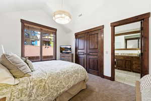 Carpeted room with vaulted ceilings and a large window featuring wood trim