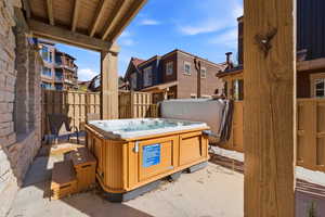 Outdoor patio featuring a hot tub with wood-finish siding and coordinating steps