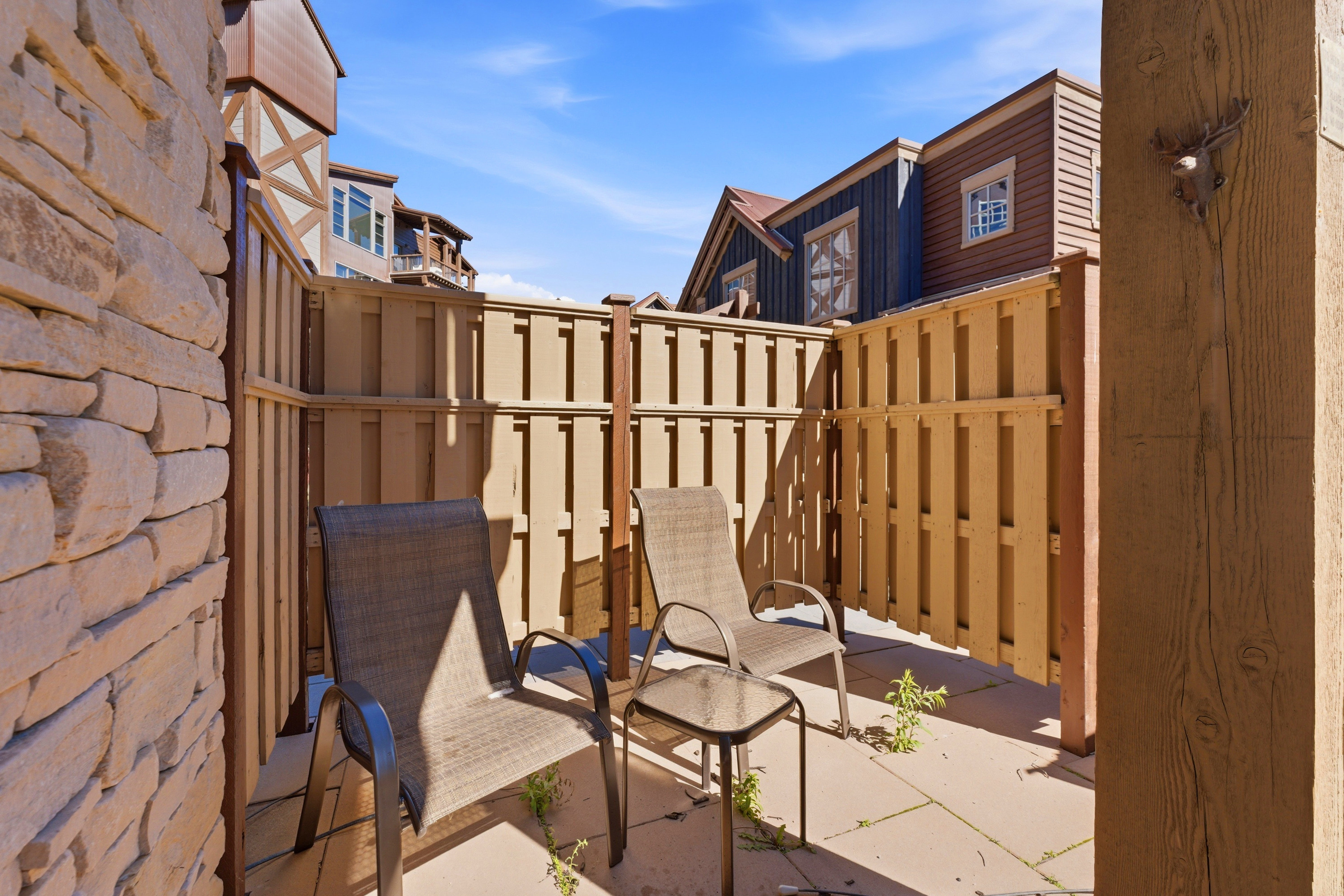Private patio featuring stone veneer wall and wood fence enclosure