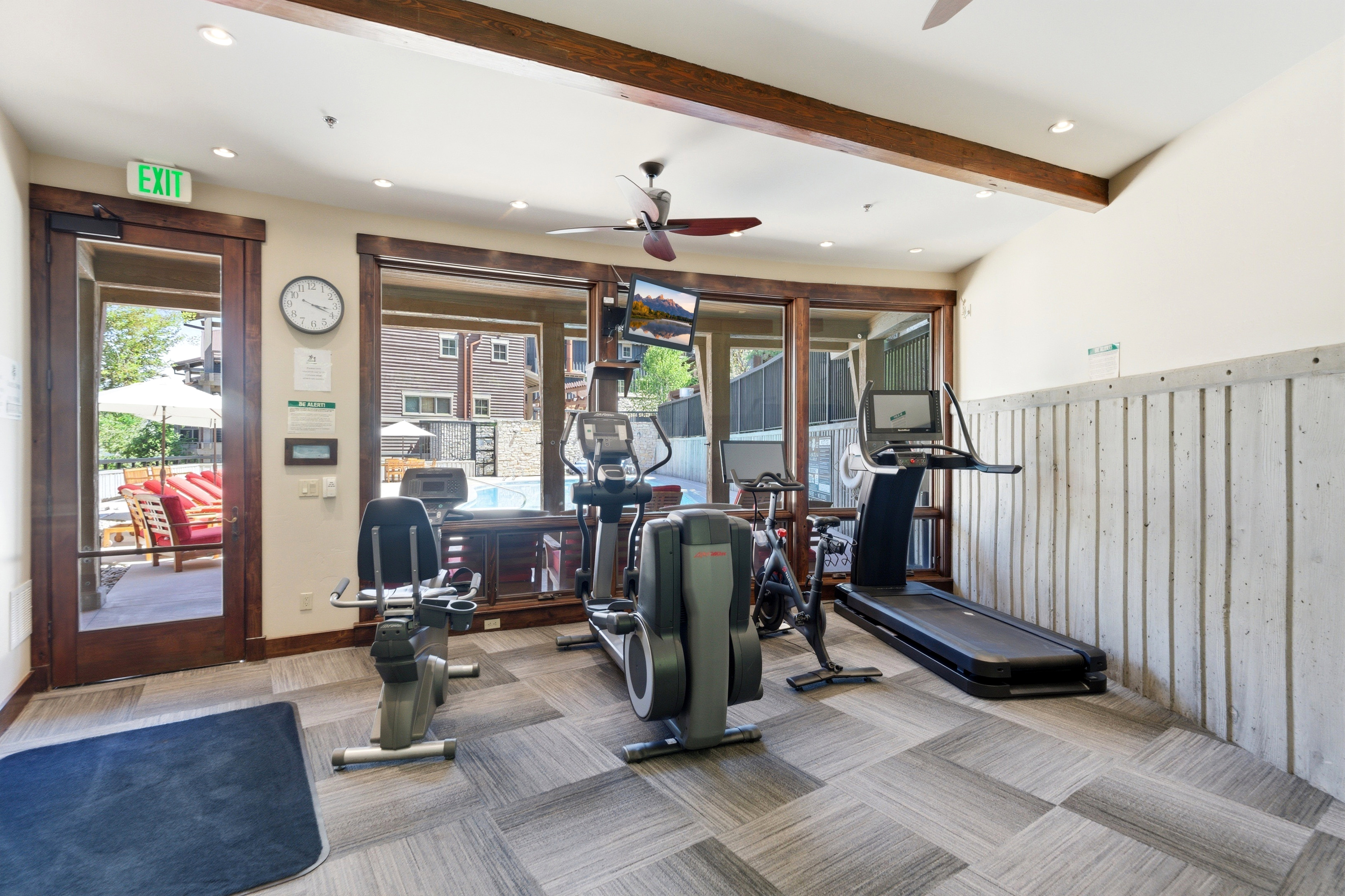 Fitness center featuring wood-finish ceiling beams, recessed lighting, and a ceiling fan