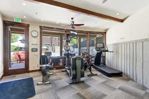Fitness center featuring wood-finish ceiling beams, recessed lighting, and a ceiling fan