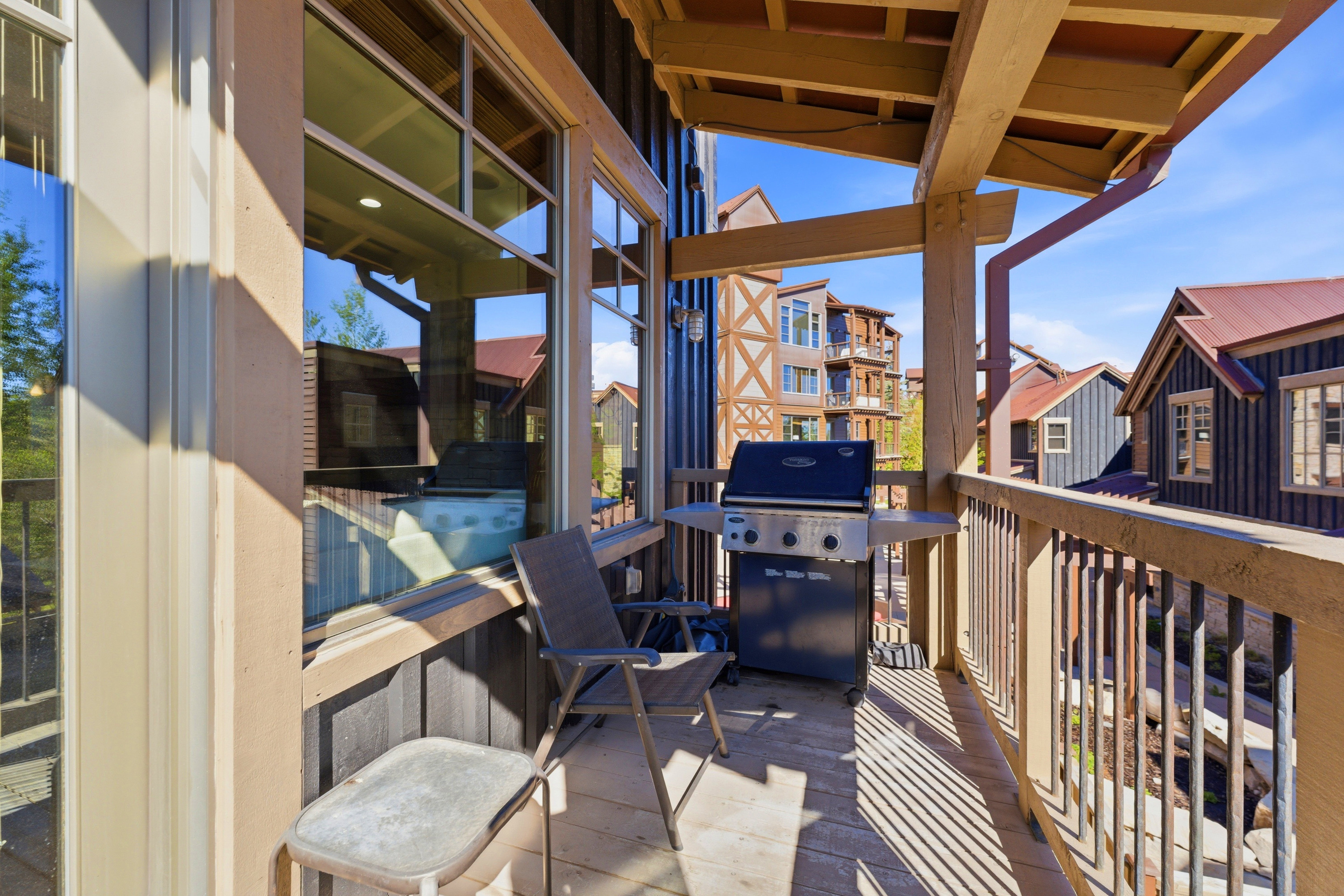 Private balcony featuring wood-finish decking, sturdy wood railings, and a wood beam overhang