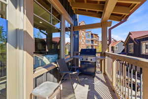 Private balcony featuring wood-finish decking, sturdy wood railings, and a wood beam overhang