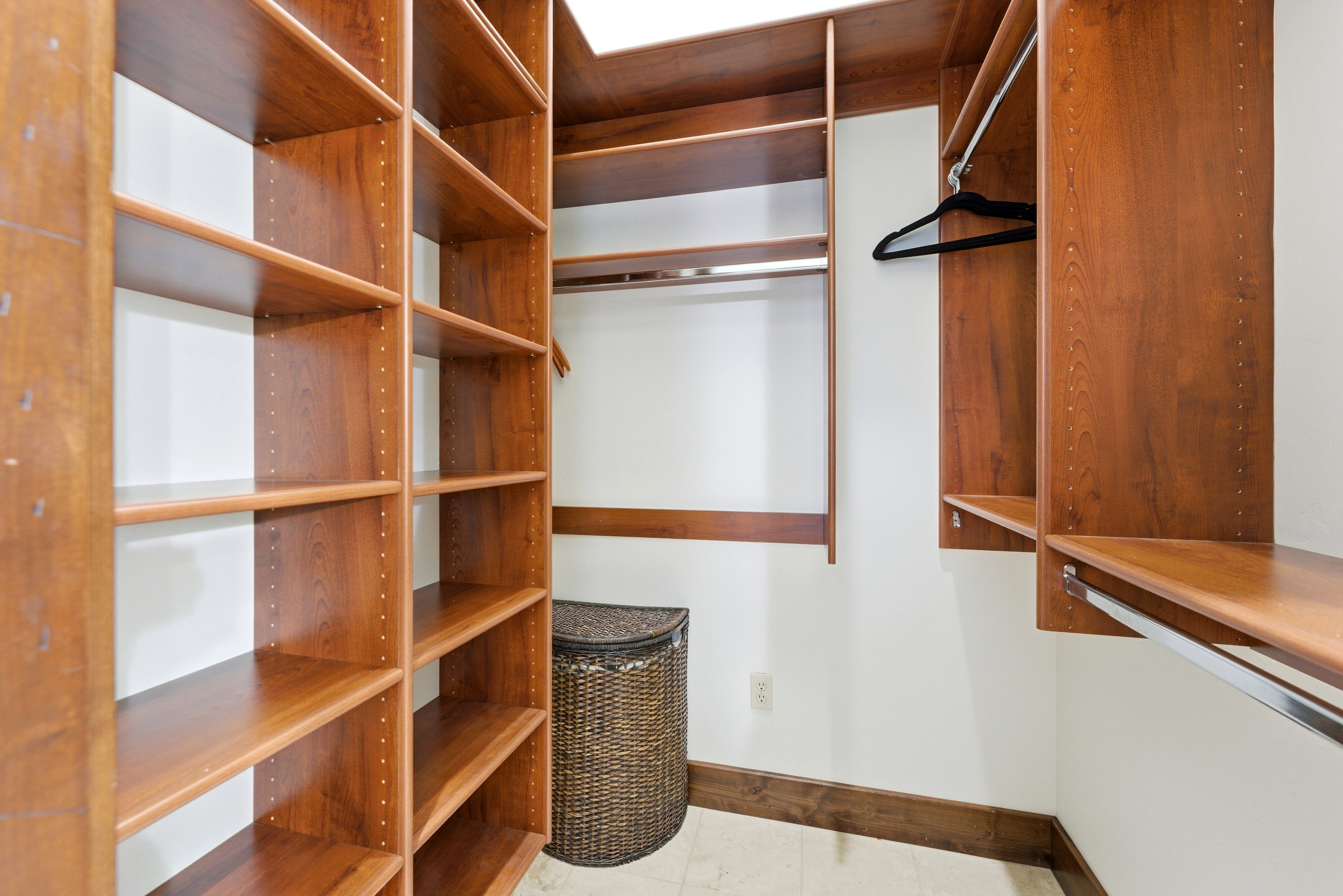 Custom closet system featuring rich wood-finish shelving, multiple hanging rods, and integrated storage solutions