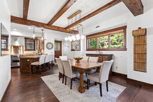 Open-concept living space with dark wood-finish flooring and exposed ceiling beams