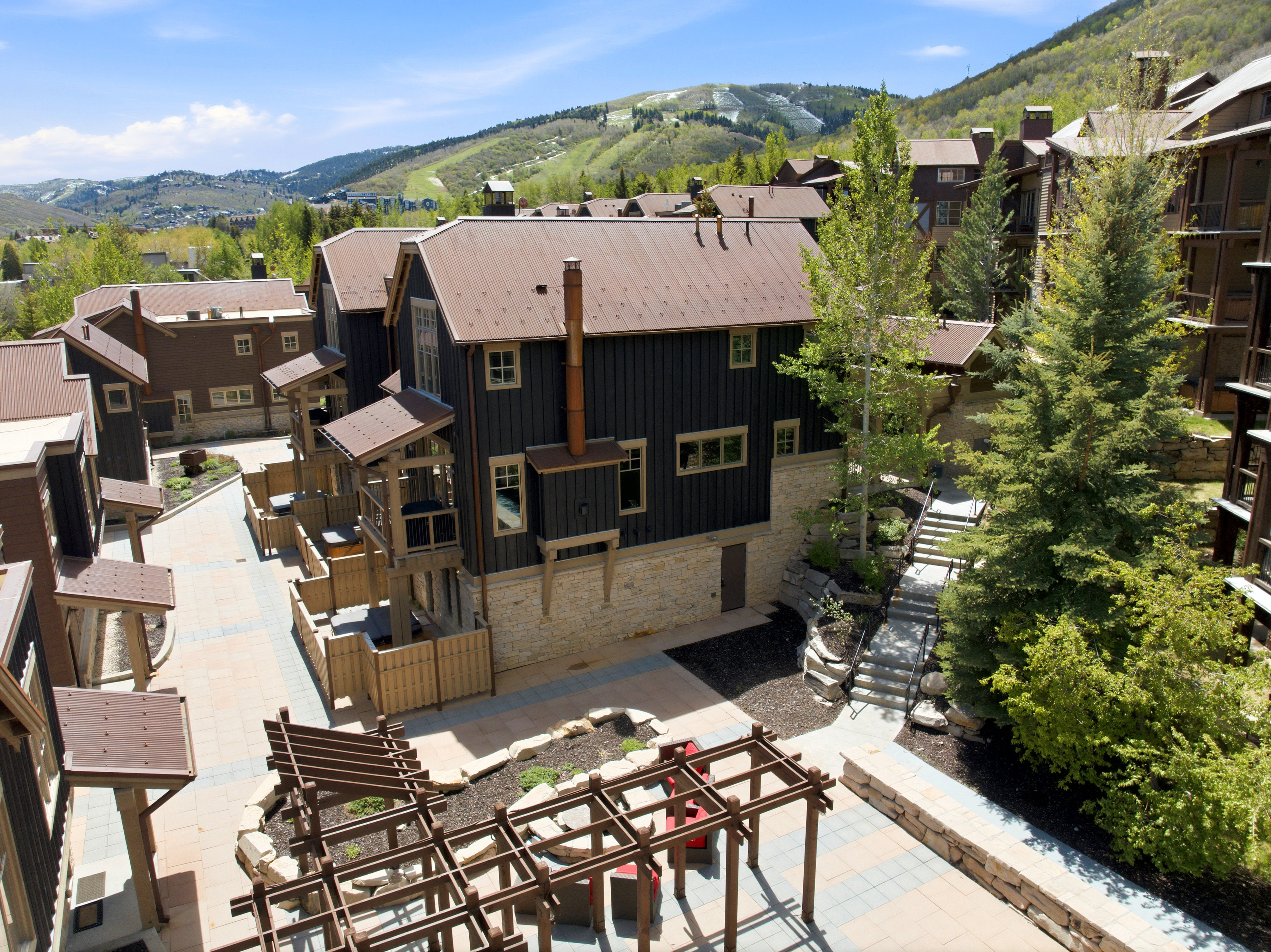 Mountain-side community featuring multi-level residences with stone and siding exteriors, metal roofs, and private patios