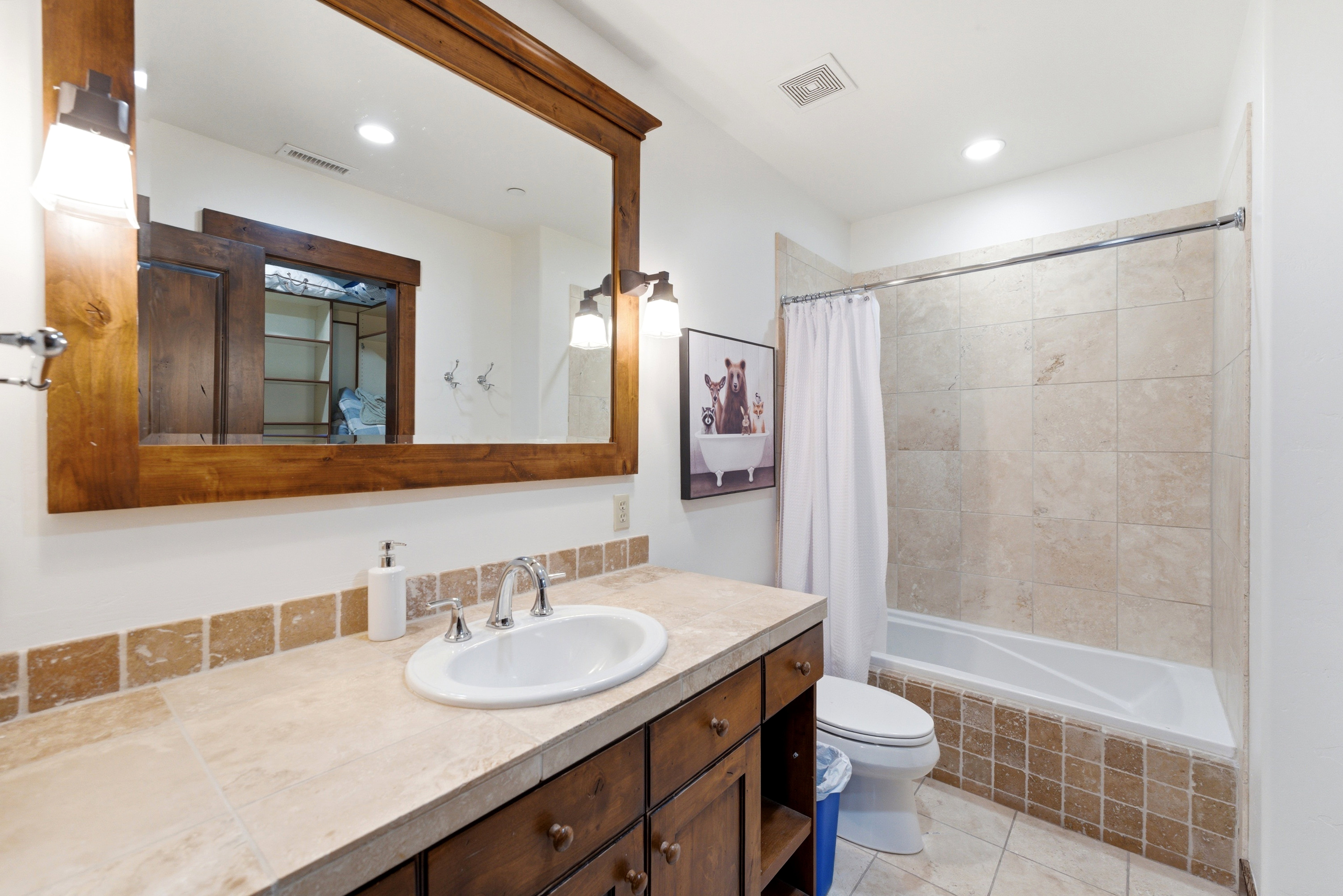 Bathroom featuring a wood-framed mirror, double sconce lighting, and a vanity with an integrated sink and base cabinetry