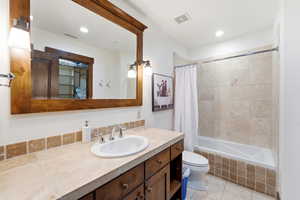 Bathroom featuring a wood-framed mirror, double sconce lighting, and a vanity with an integrated sink and base cabinetry