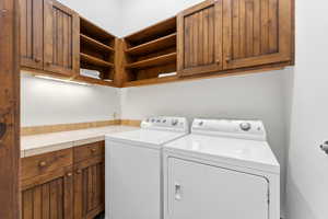 Laundry room featuring wood cabinetry, open shelving, stone countertop, and under-cabinet lighting