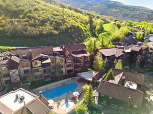 Multi-story complex featuring a large outdoor swimming pool and a separate hot tub