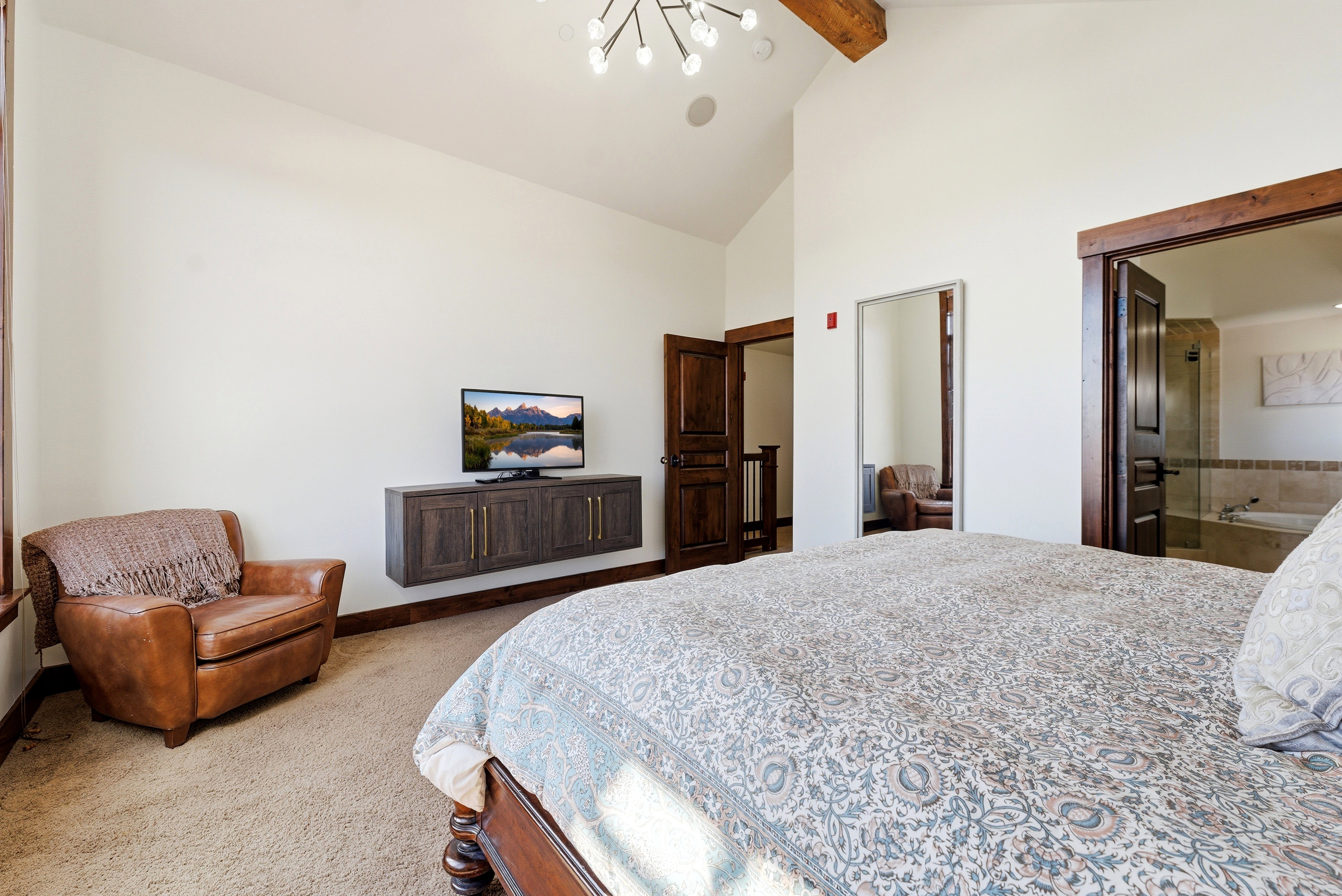 Spacious room featuring vaulted ceilings with exposed wood beams, a built-in wall cabinet, and dark wood trim accents
