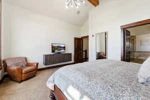 Spacious room featuring vaulted ceilings with exposed wood beams, a built-in wall cabinet, and dark wood trim accents
