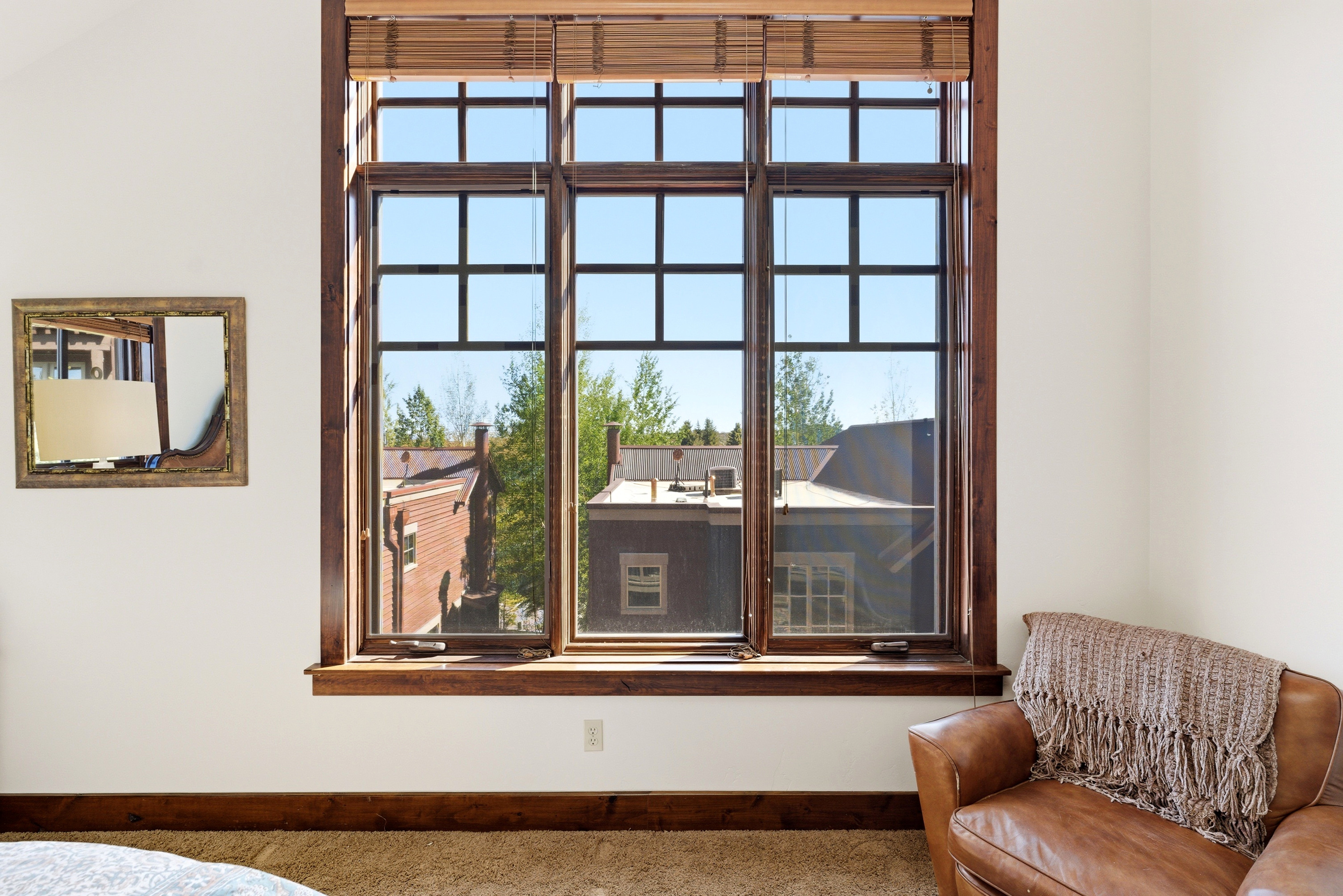 Large multi-pane window with dark wood-finish framing, wood-finish blinds, and a deep sill