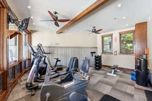 Fitness area featuring geometric patterned carpet, exposed wooden ceiling beams, recessed lighting, and dual ceiling fans