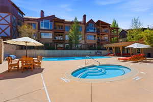 Resort-style outdoor amenities featuring a large swimming pool, a circular hot tub, and an inviting poolside deck