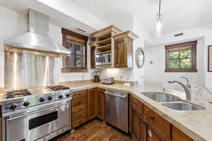 Kitchen featuring a stainless steel range with griddle, coordinating range hood, and double basin sink