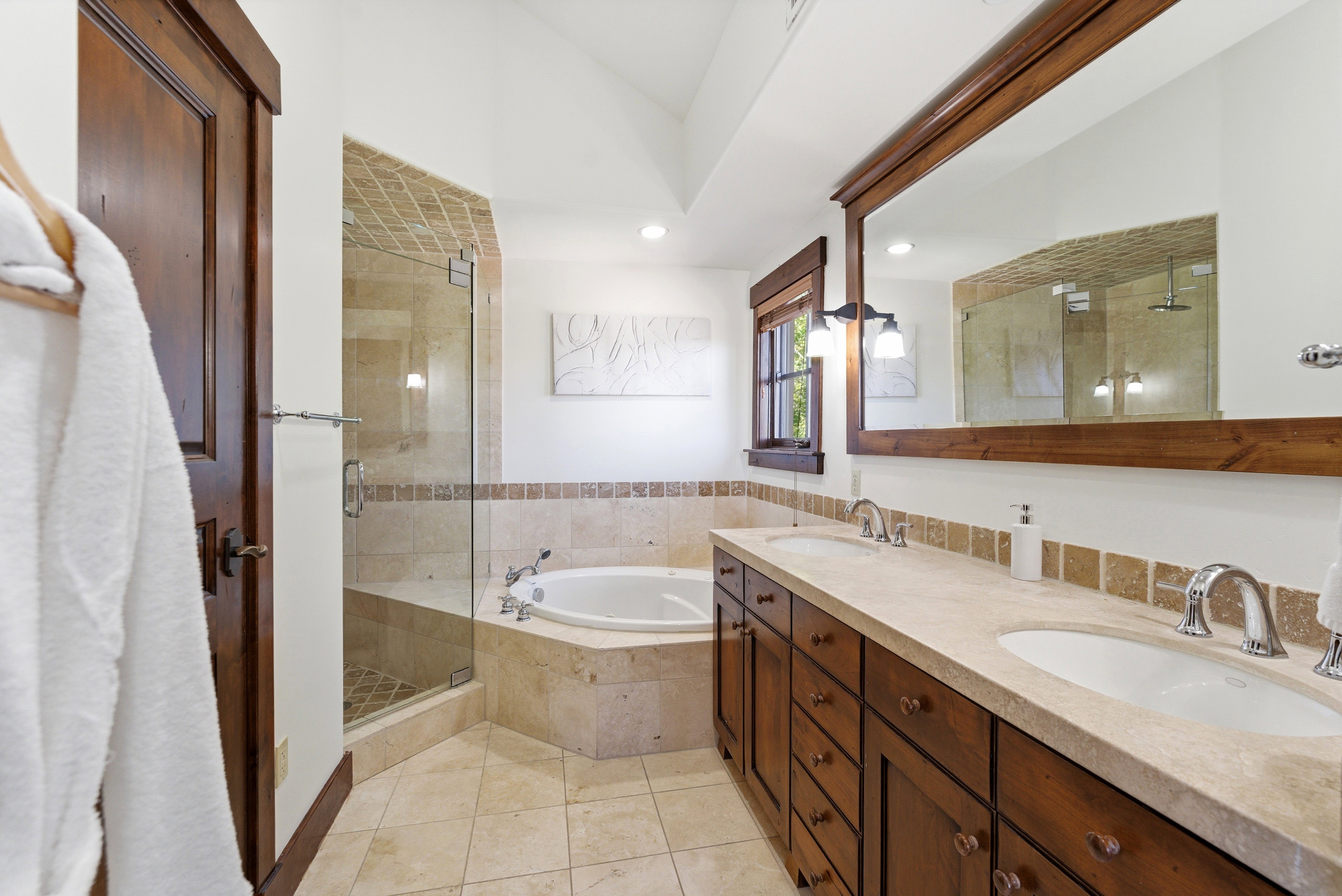 Bathroom featuring a dual vanity with a light-toned countertop, wood cabinetry, and a large framed mirror