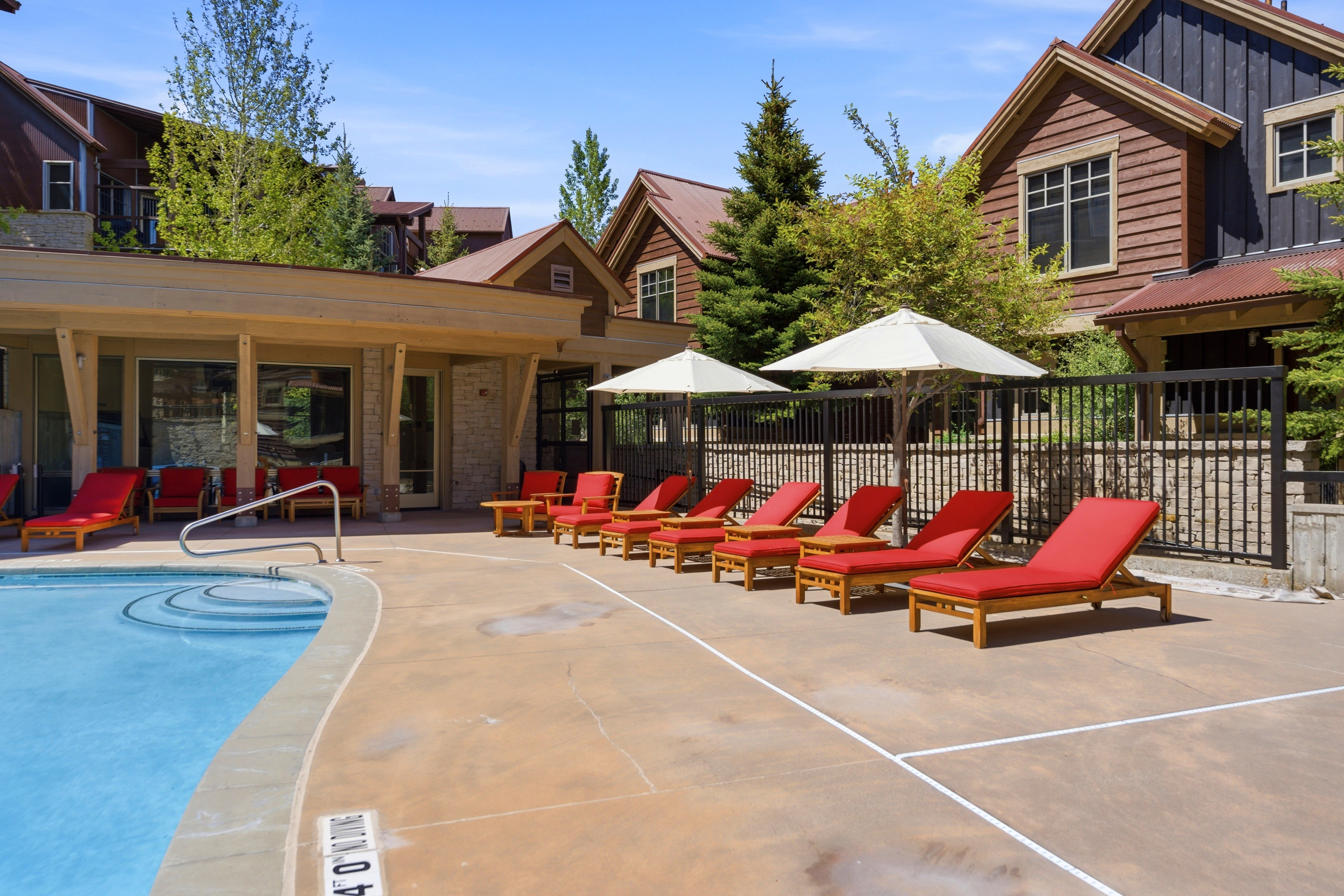 Outdoor swimming pool featuring integrated steps and a metal handrail