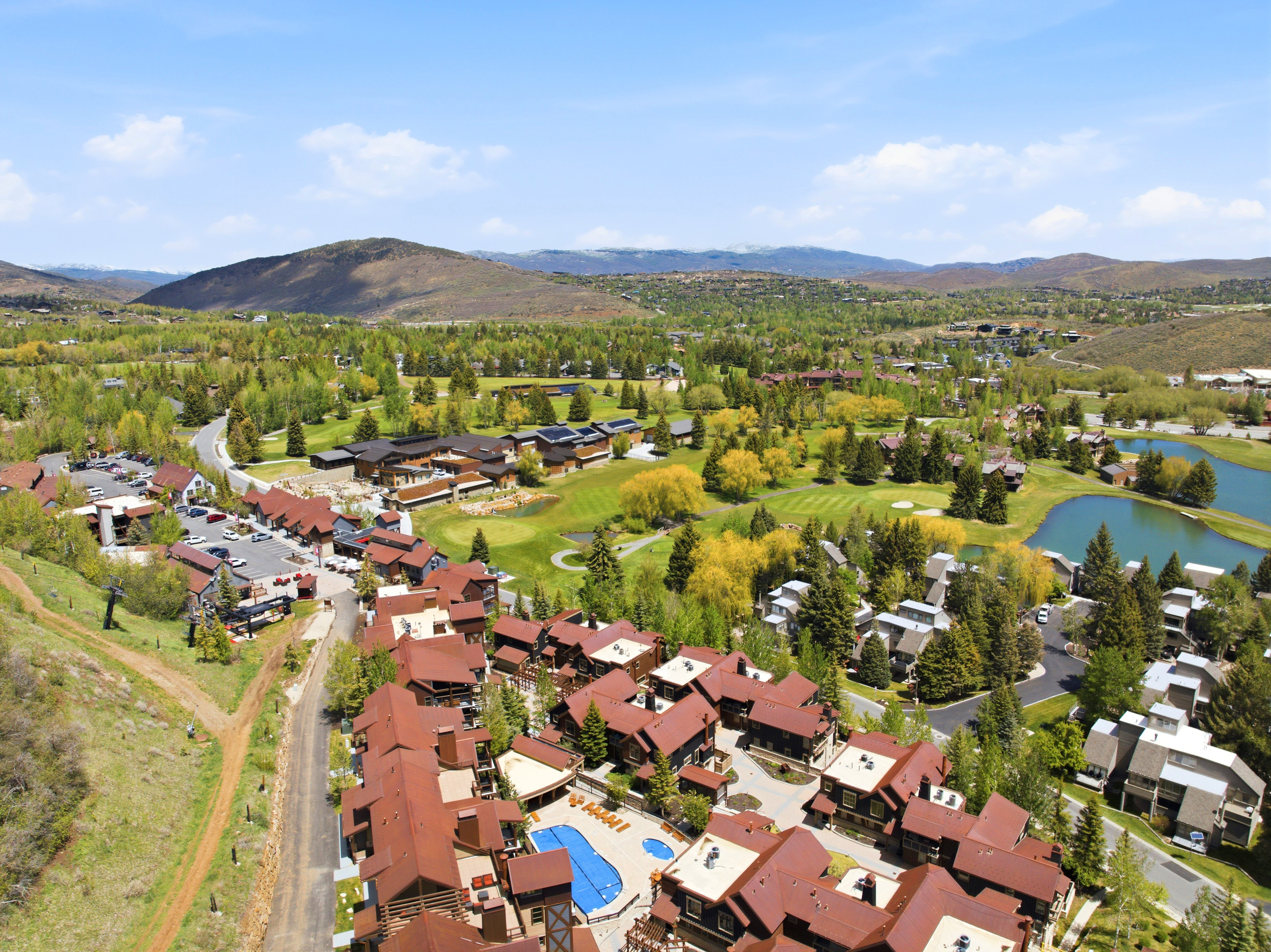 Aerial perspective showcasing a community with varied architectural styles, a central outdoor pool, and surrounding green spaces